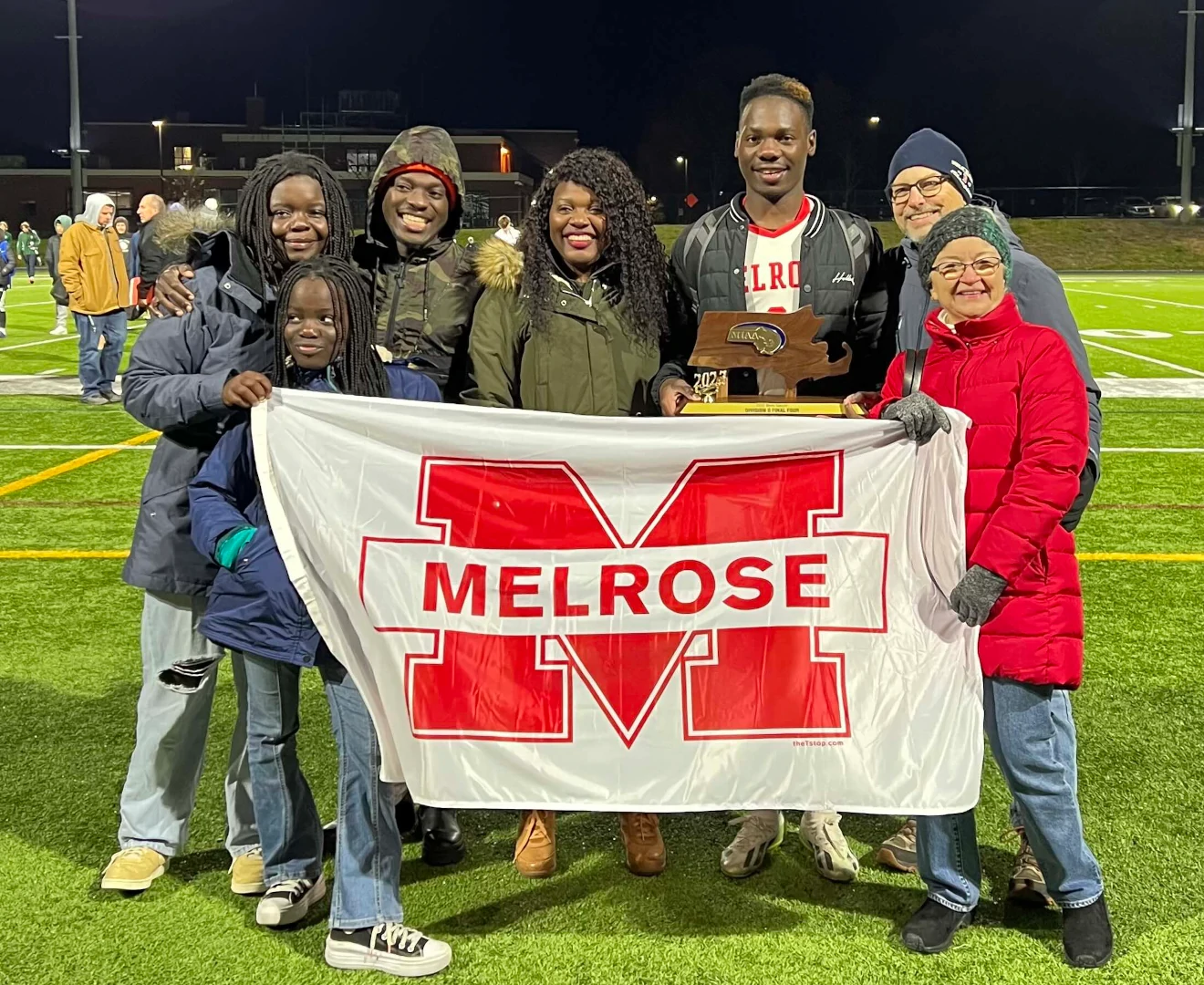 A Ugandan immigrant family: mother and four children, celebrate a high school soccer victory featuring the second oldest son with two Immigrant Support Alliance volunteers.