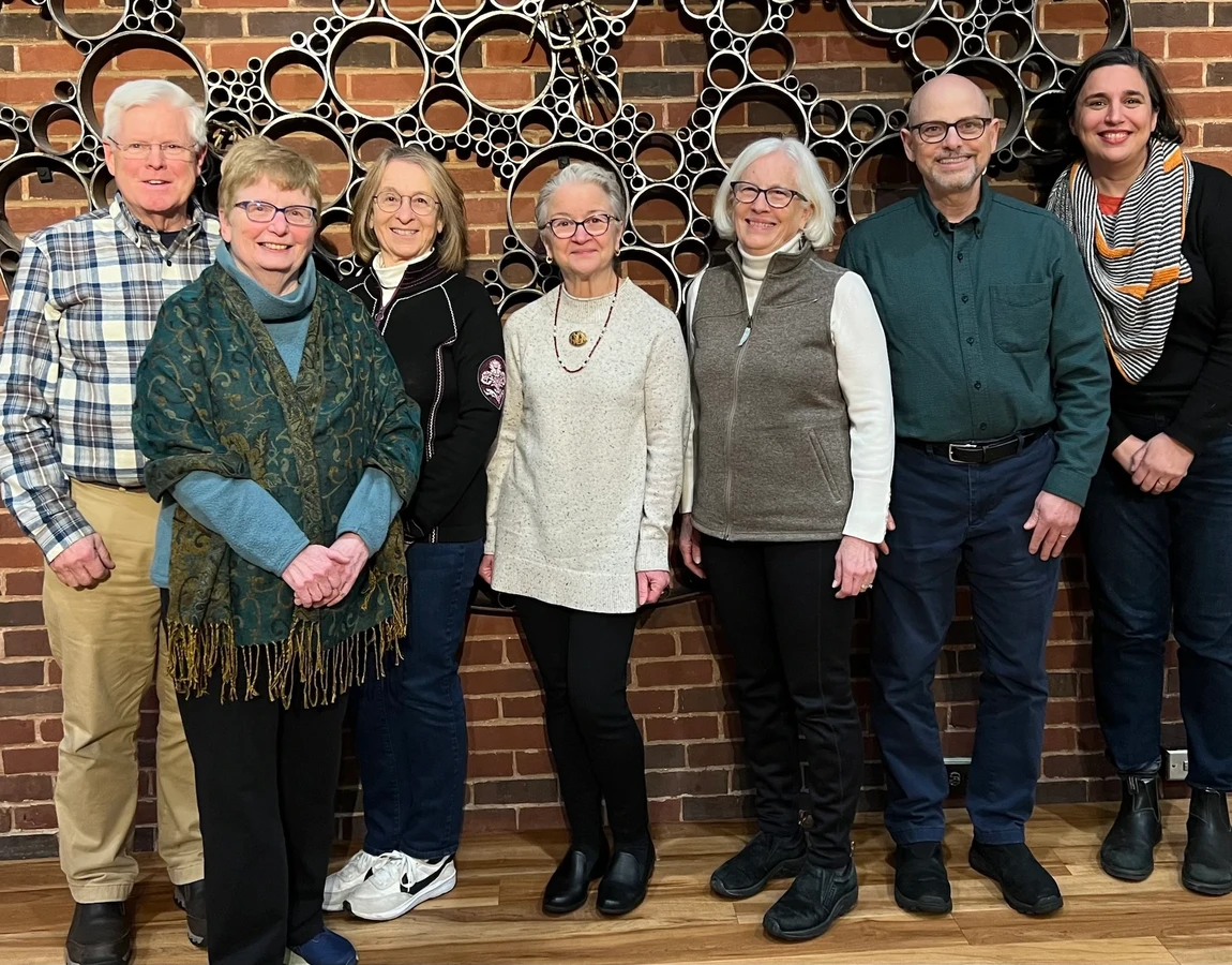 A group of seven adults representing the Immigrant Support Alliance Steering Committee. Left to Right: Bruce Alexander, Treasurer, Linda Alexander, Maureen Curley, Michelle Desveaux, Debbie Anderson, Paul Belfanti, President, Anne Pessala