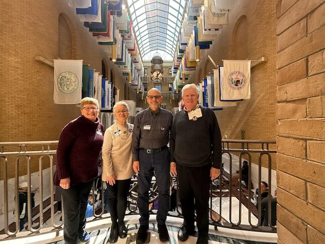 Members of the Immigrant Support Alliance Steering Committee in front of the Hall of Flags at the Massachusetts State House